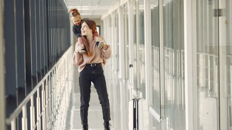 A mother and daughter travelling together with a suitcase.